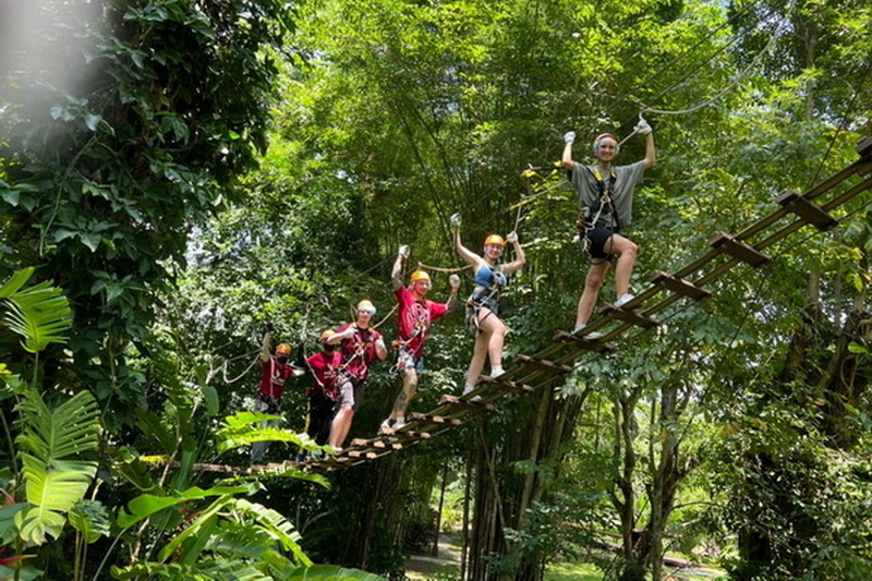 Adventure Park Bridge Crossing at Phoenix Adventure Park Group of people on a suspension bridge surrounded by lush forest greenery at Phoenix Adventure Park.