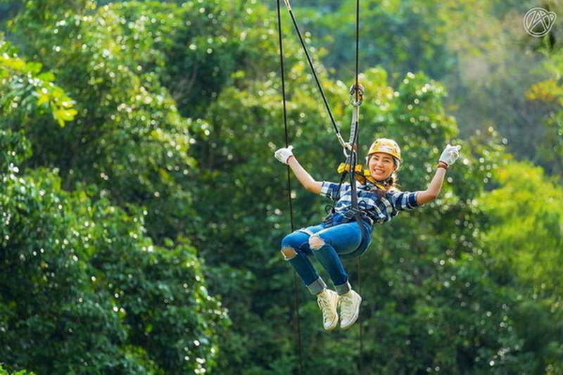 Zip-Lining Adventure in Forest at Phoenix Zipline Chiang Mai Woman zip-lining through the trees in a forest during daytime at Phoenix Zipline Chiang Mai.