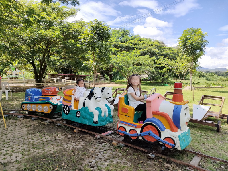 Children's Train Ride in Park at Phoenix Adventure Park Two young girls riding a bright, colorful children's train in a park at Phoenix Adventure Park.