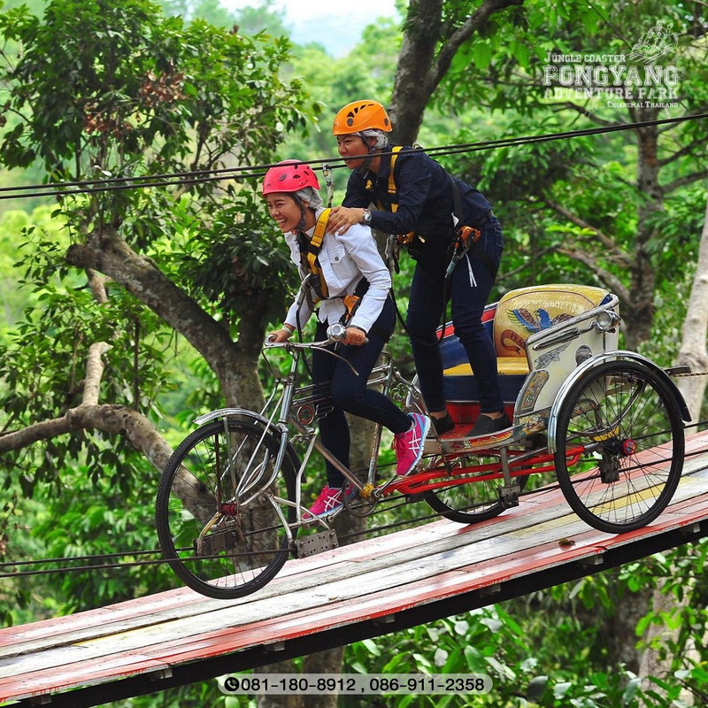 Tandem Bicycle Ride Over Forest Bridge at Pong Yang Zipline Woman and girl riding tandem bicycle on a wooden bridge in lush greenery at Pong Yang Zipline.