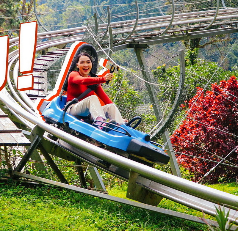 Exciting Roller Coaster Ride at Pong Yang Zipline Woman riding a roller coaster with a joyful expression amidst trees and greenery at Pong Yang Zipline.
