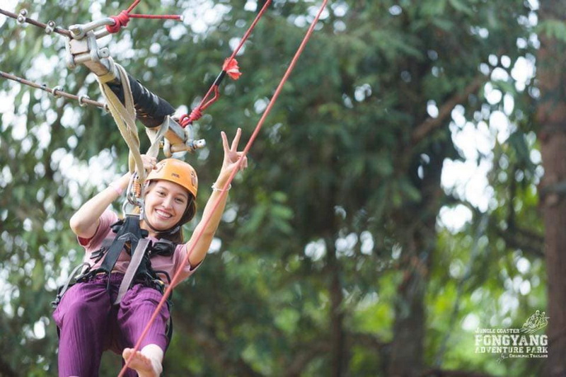 Zipline Adventure Smile at Pong Yang Zipline Woman in helmet smiling and making a peace sign on a zipline in the forest at Pong Yang Zipline.
