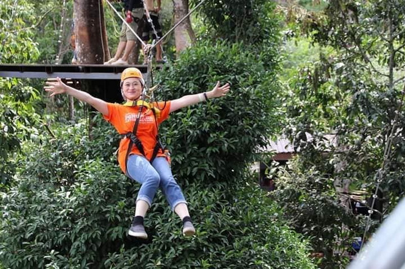 Zipline Adventure in Nature at Pong Yang Zipline Woman in orange shirt and helmet riding a zipline through trees at Pong Yang Zipline.