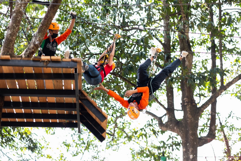 Ziplining Adventure at Pong Yang Zipline Person ziplining upside down with helmet in a forested area at Pong Yang Zipline.