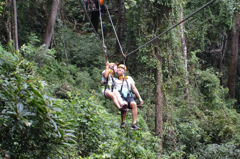 Zip Line Adventure in Jungle at Skyline Jungle Luge Two individuals on a zip line flying through a lush forest canopy at Skyline Jungle Luge.