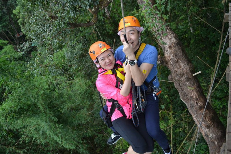 Outdoor Tree Adventure at Chiang Mai Skyline Adventure Two adventurers in helmets and harnesses hanging among trees during outdoor activity at Chiang Mai Skyline Adventure.