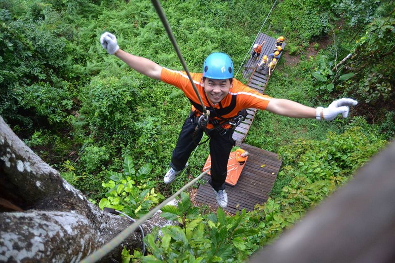 Forest Zip Line Adventure at Skyline Jungle Luge Person wearing helmet and harness on a zip line over dense forest canopy at Skyline Jungle Luge.