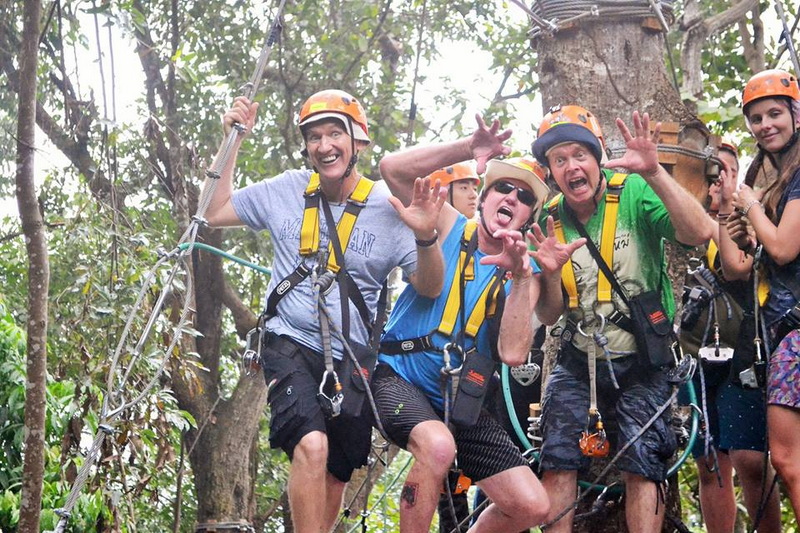People in helmets and harnesses enjoying a forest adventure activity at Skyline Jungle Luge.