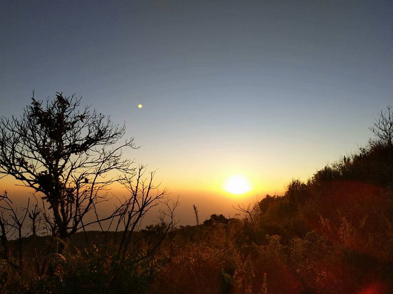 Sunset View Over Hills at Doi Luang Chiang Dao Sunset over a hillside with silhouetted trees and a bright horizon sky at Doi Luang Chiang Dao.