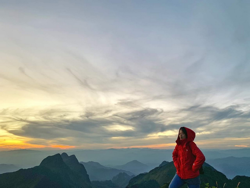 Sunset View from Mountain Ridge at Doi Luang Chiang Dao Woman in red jacket on mountain ridge at sunset with layered mountains and sky at Doi Luang Chiang Dao.