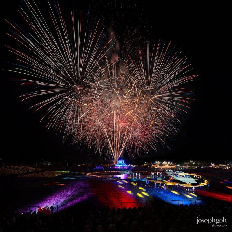 Fireworks illuminating the night sky over boats on water with colorful lights at New Year Countdown Chiang Mai by CAD.