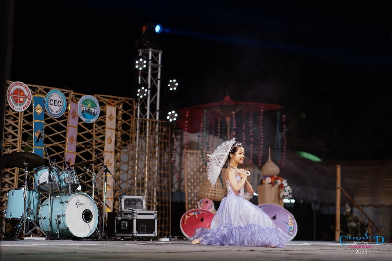 Night Performance at Chiang Mai at New Year Countdown Chiang Mai by CAD Woman in purple dress with lace umbrella sitting on stage at night with musical instruments nearby at New Year Countdown Chiang Mai by CAD.