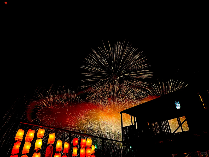 Colorful fireworks light up the night sky above lantern-lined structure at Yi Peng Chiang Mai.