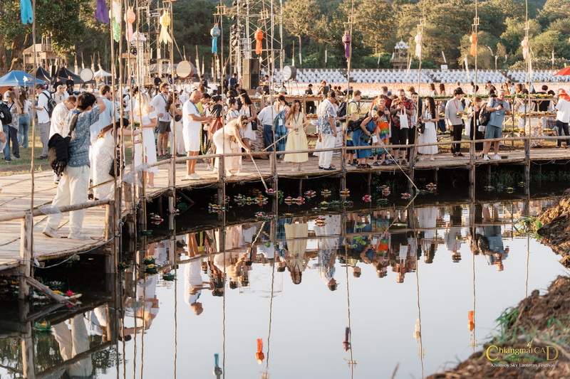Gathering on Wooden Bridge at Yi Peng Chiang Mai Crowd gathered on a wooden bridge over a pond with floating lotus flowers at Yi Peng Chiang Mai.