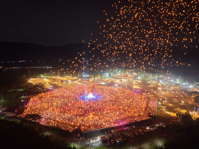 Crowd releasing sky lanterns during a nighttime festival scene at Yi Peng Chiang Mai.