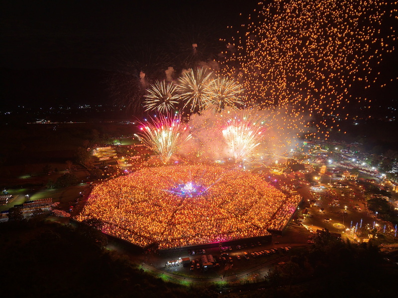 Lantern Festival Night Scene at Yi Peng Chiang Mai Thousands of floating lanterns and fireworks illuminate the night sky in a festive outdoor setting at Yi Peng Chiang Mai.