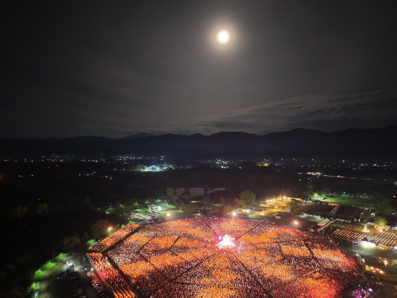 Lantern Festival Night Sky at Yi Peng Chiang Mai Night scene with floating lanterns over a mountainous landscape illuminated below at Yi Peng Chiang Mai.