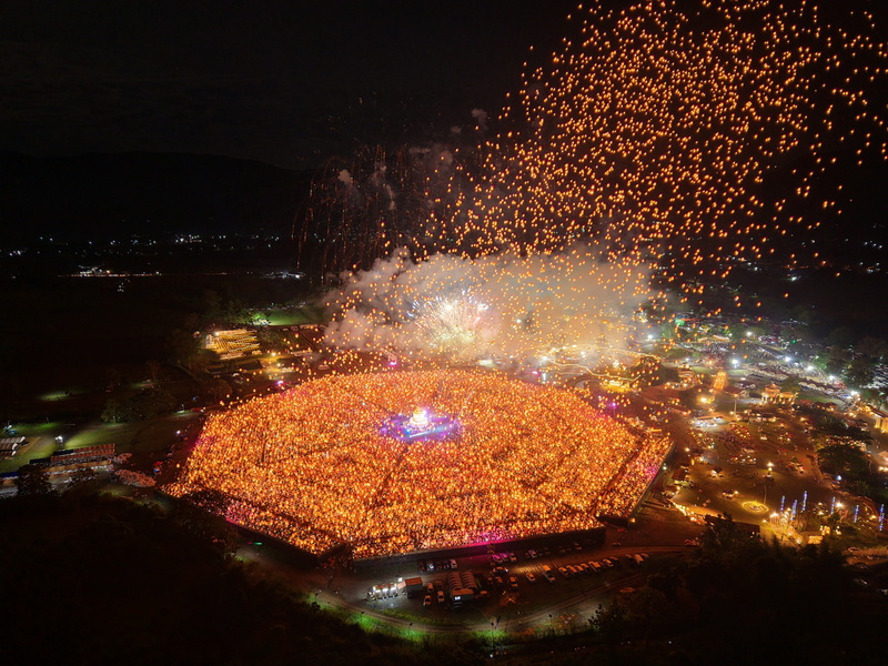 Crowd releasing lanterns at night during a festival with fireworks overhead at Yi Peng Chiang Mai.