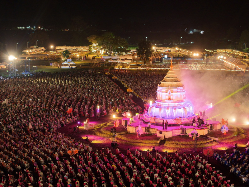 Night Gathering with Illuminated Monument at Yi Peng Chiang Mai Night scene with a large illuminated monument surrounded by a crowd of people at Yi Peng Chiang Mai.