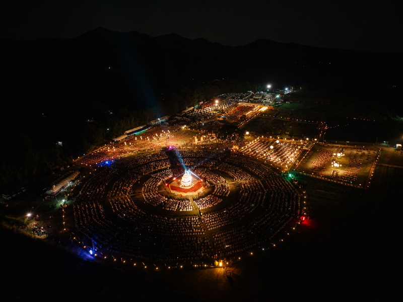 Night Festival with Circular Lights at Yi Peng Chiang Mai Aerial night scene of an outdoor circular event with lights and tents around a central monument at Yi Peng Chiang Mai.