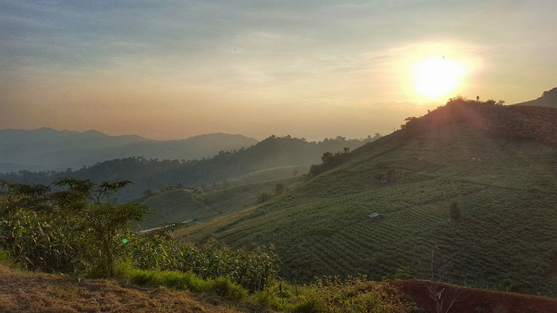 Sunset illuminating rolling green hills and distant mountains at Mon Jam.