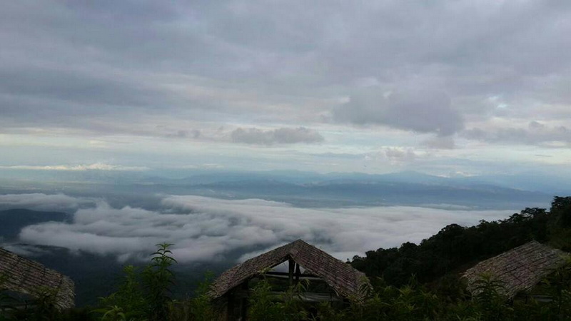 Mountains covered in clouds view from a rustic mountain viewpoint with forest below at Mon Jam.