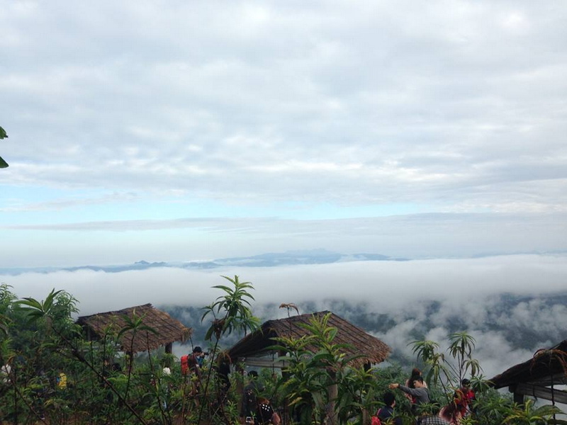 Cloudscape view over mountains with huts and greenery in foreground at Mon Jam.