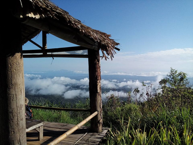 Mountain Viewpoint Over Clouds at Mon Jam Wooden hut with thatched roof overlooking clouds and sky from a mountain viewpoint at Mon Jam.