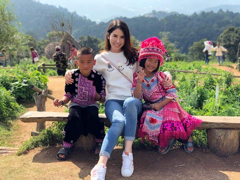Children and a woman sitting on a bench surrounded by greenery and hills at Mon Jam.