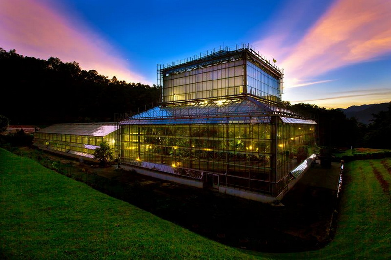 Illuminated Glass Building at Dusk at Chiang Mai Gardens Modern glass building with multiple levels and reflective windows at sunset at Chiang Mai Gardens.