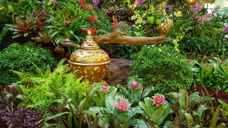 Decorative ceramic jar among vibrant flowers and green plants in a garden setting at Royal Flora Ratchaphruek.