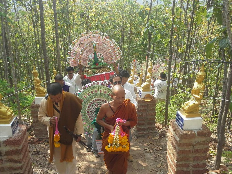 Forest Procession with Buddha Statues at Wat Phra That in Kwaen Monks and participants in a forest procession carrying Buddha statues and floral decorations at Wat Phra That in Kwaen.