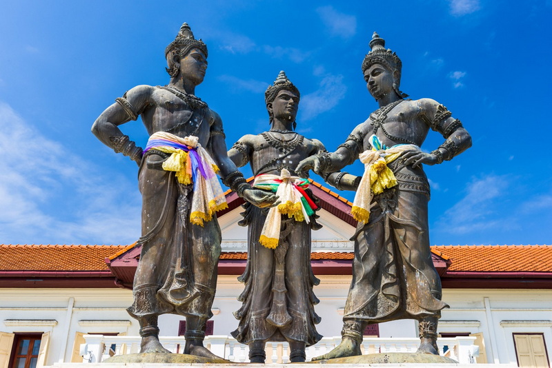 Thai Dancer Statues at Three kings Monument Three Thai traditional dancer statues with colorful cloths and a building behind them at Three kings Monument.