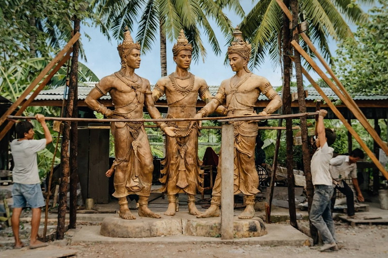 Wooden Thai Statue Assembly at Three King Monument Workers assembling wooden statues of Thai figures outdoors with scaffolding at Three King Monument.