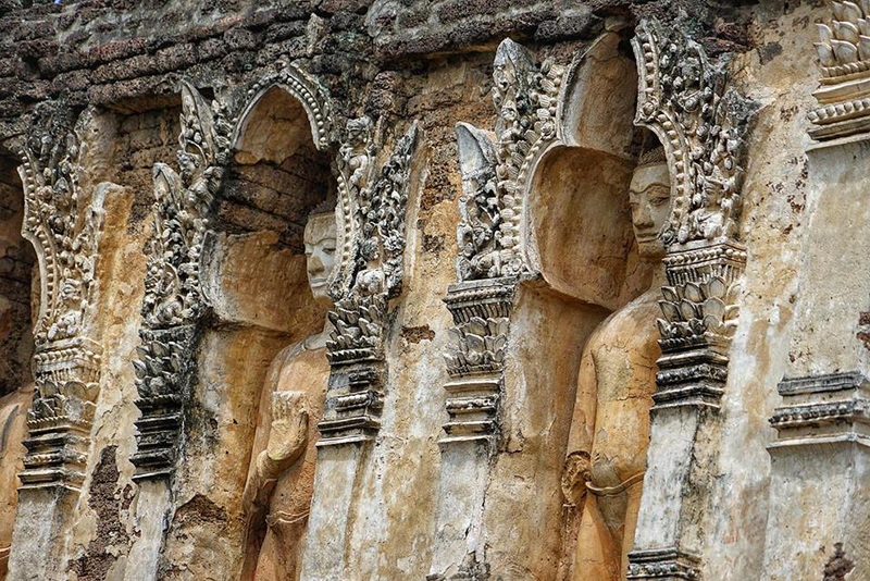 Carved Buddha Statues in Temple at Chamadevi Temple Stone wall with carved Buddha statues and ornate arches in an ancient temple at Chamadevi Temple.