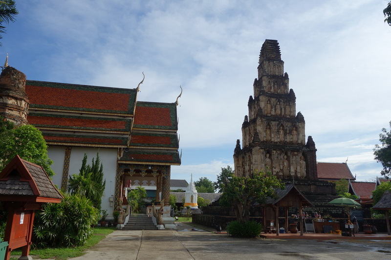 Ancient temple with a tall pagoda and traditional Thai roof in a lush setting at Wat Chamadevi.