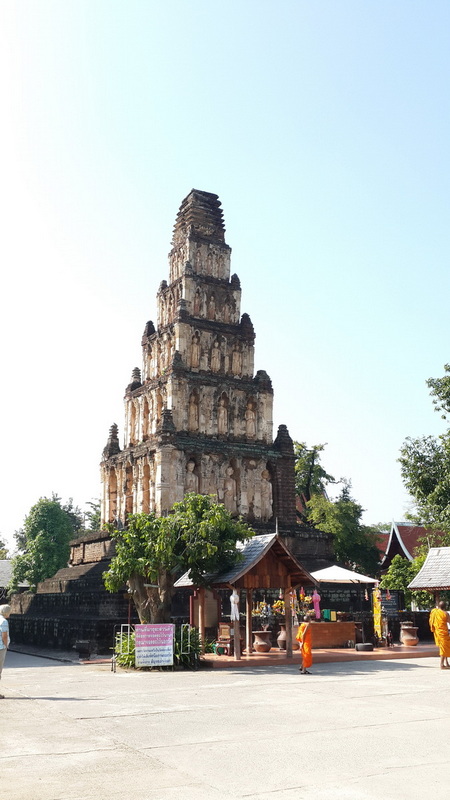 Ancient Stone Pagoda at Chamadevi Temple An ancient stone pagoda with multiple tiers and detailed carvings near greenery at Chamadevi Temple.
