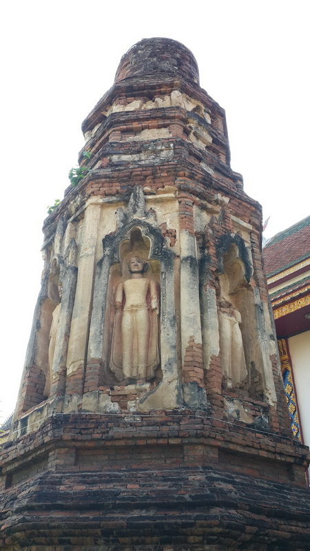 A historic brick and stucco stupa with carved statues on its sides at Wat Chamadevi.