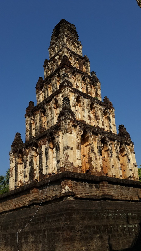 Ancient Stone Pagoda at Chamadevi Temple Tall ancient stone pagoda with detailed carvings and multiple tiers against a clear sky at Chamadevi Temple.