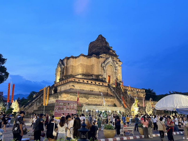 Illuminated Temple Stupa at Dusk at Wat Chedi Luang Ancient temple stupa lit up with visitors and vendors around it during evening at Wat Chedi Luang.