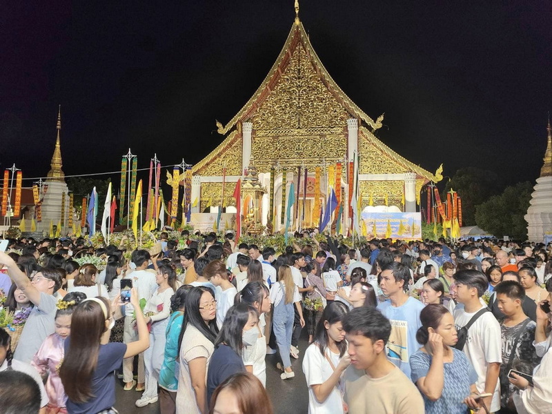 Night at the Golden Temple at Wat Chedi Luang Crowd of visitors outside a gold-temple at night with colorful flags at Wat Chedi Luang.