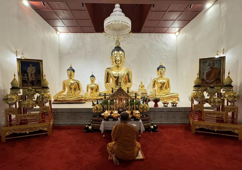 Inner View of Buddha Temple at Wat Chedi Luang Person kneeling in prayer before four golden Buddha statues inside a temple room at Wat Chedi Luang.
