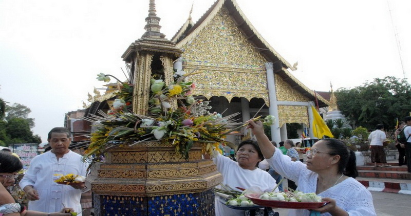 Traditional Ceremony Outside Golden Temple at Chedi Luang temple Individuals offering flowers during a ceremony outside a decorated golden temple at Chedi Luang temple.