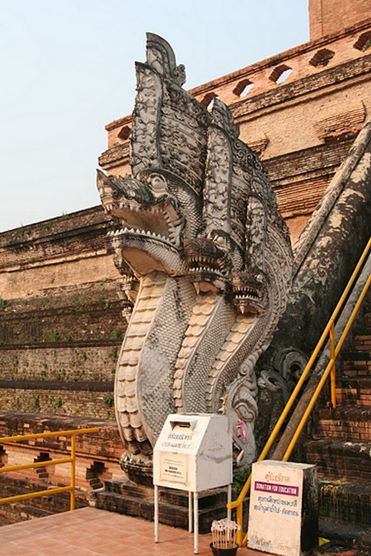 Naga Sculpture at Ancient Site at Wat Chedi Luang Stone Naga sculpture with multiple heads and ornate backrest against brick walls at Wat Chedi Luang.