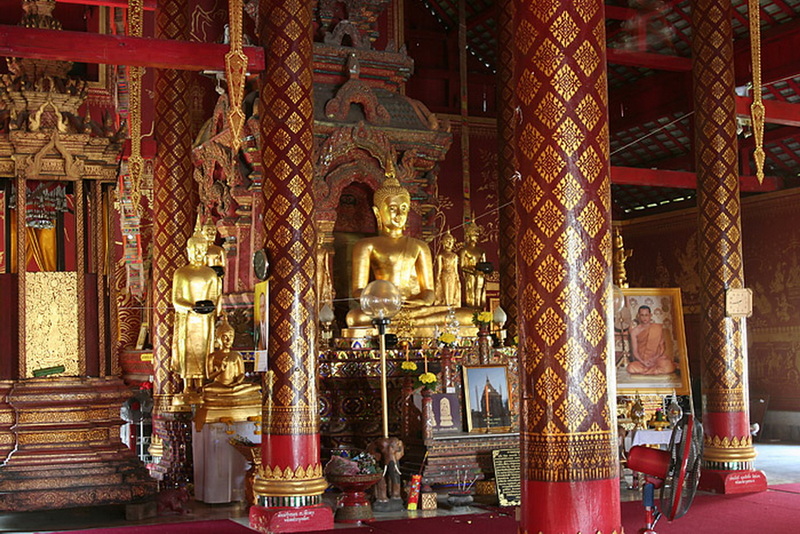 Temple Interior with Buddha Statues at Wat Chiang Man Inside a temple with golden Buddha statues and red decorative pillars at Wat Chiang Man.