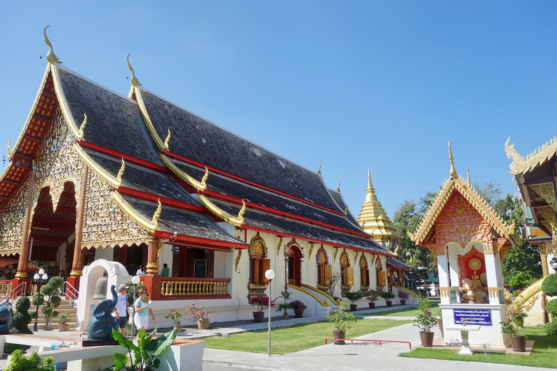 Traditional Thai temple with golden accents and intricate details under a blue sky at Wat Chiang Man.