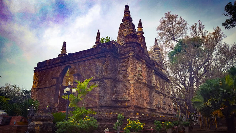 Ancient Temple with Spires at Wat Jed Yod Ancient brick temple with multiple spires surrounded by trees and greenery at Wat Jed Yod.