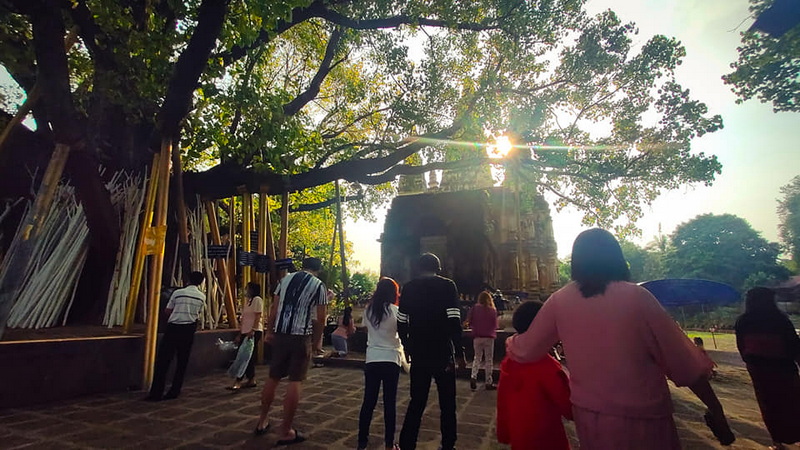 Group of people standing outside an old stone structure in a park setting at Wat Jed Yod.