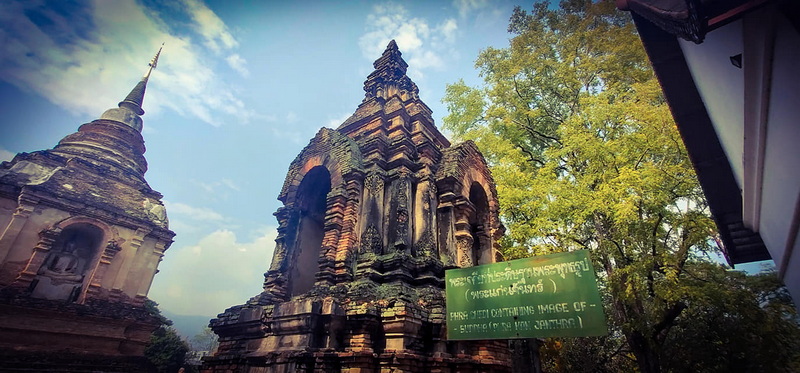 Ancient stone pagoda and stupa with layered design surrounded by trees at Wat Jed Yod.