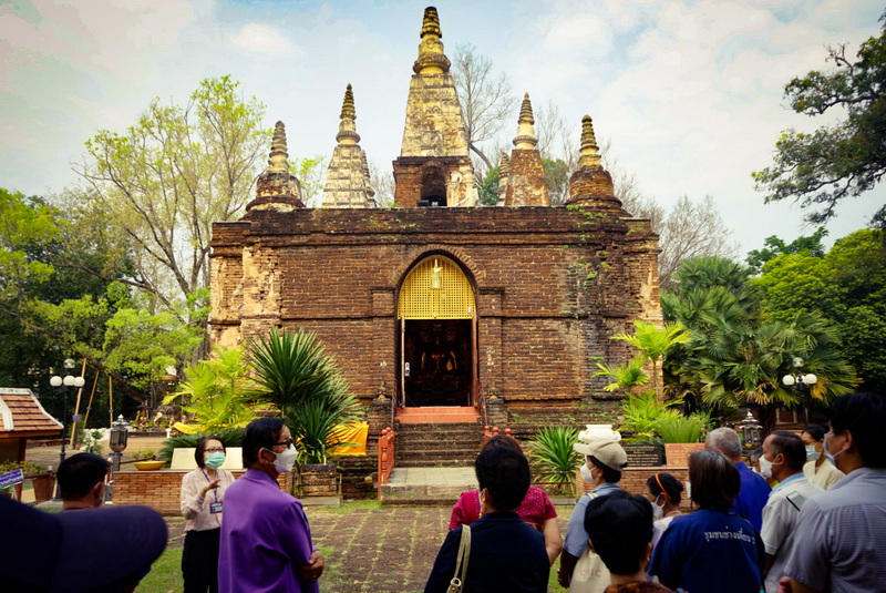 Ancient Stupa with Spires at Wat Jed Yod Brick stupa with small spires surrounded by greenery and visitors gathering at Wat Jed Yod.